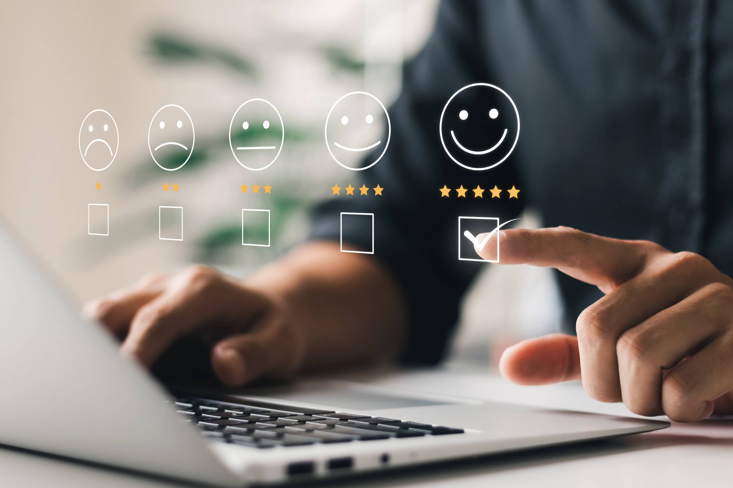 Using a market research platform, a person selects a checkbox on a virtual rating scale that ranges from a sad face to a happy face, complete with five stars above the happy face, all while using a laptop.