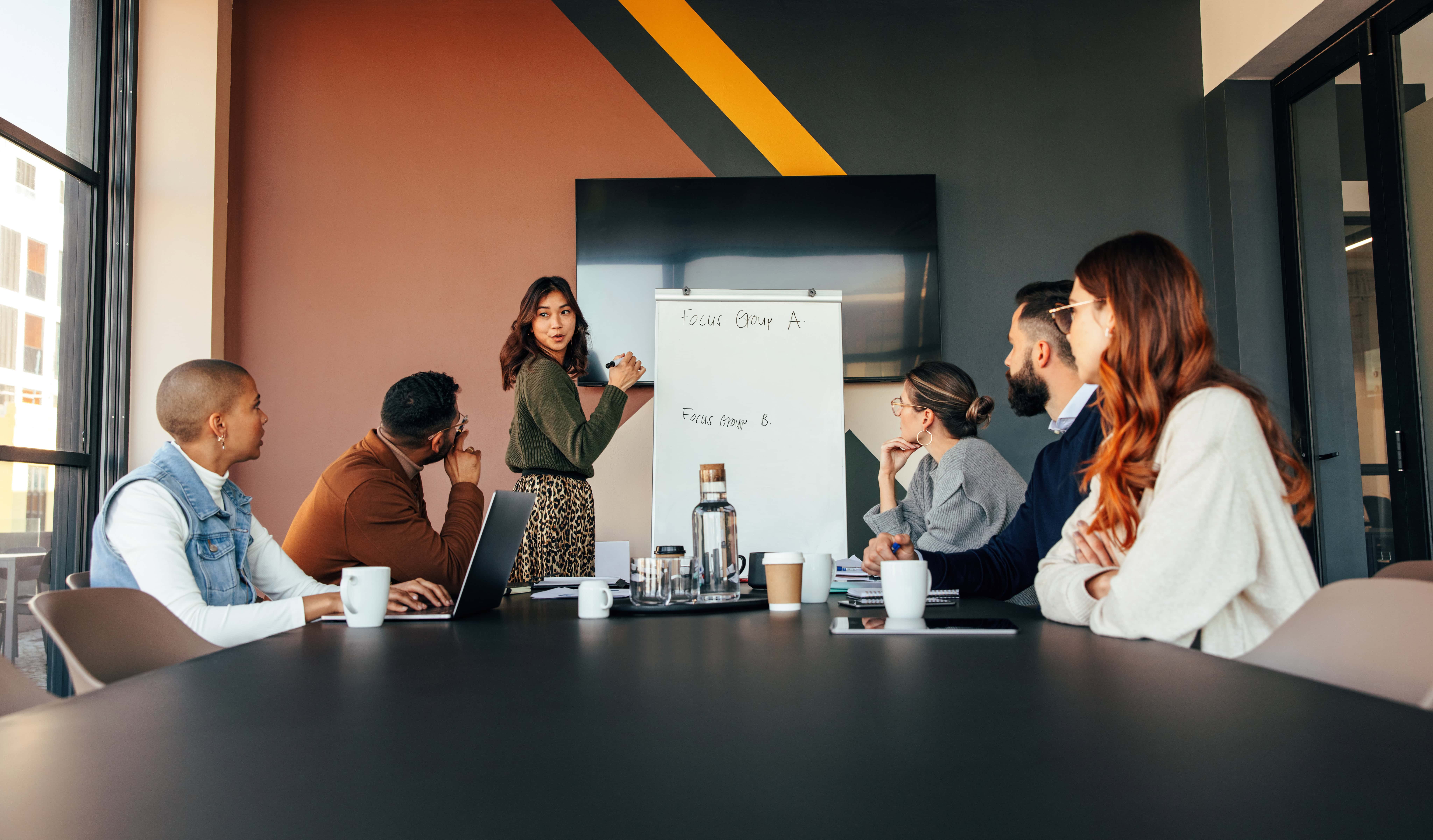 Smart businesswoman giving a presentation in a boardroom. Businesswoman presenting her business strategy to her colleagues. Group of multiracial entrepreneurs having a meting in a modern office.