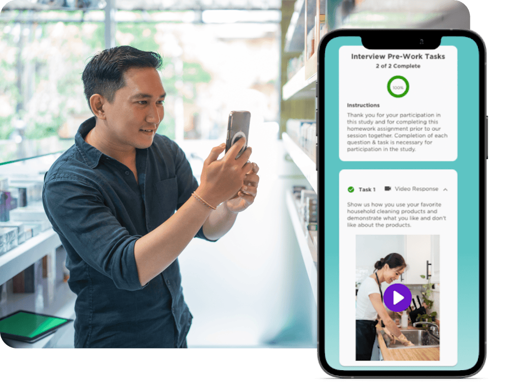 A man is using a smartphone in a brightly lit room. A digital screen next to him shows an interview pre-work task completion interface with text and a video response section.