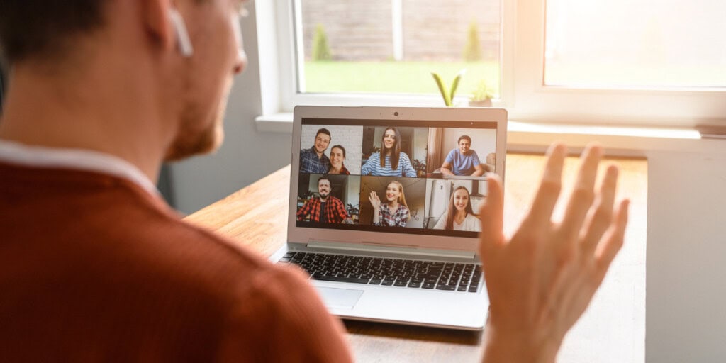 Person participating in a video conference call with six people displayed on a laptop screen.